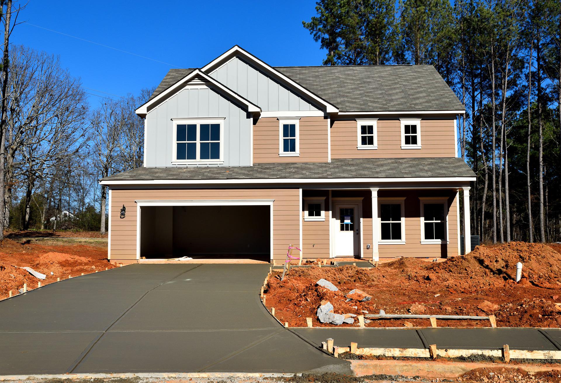 house-3084040_1920 Two-story house with garage and driveway under construction, surrounded by dirt and trees.