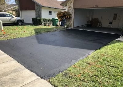 Asphalt Driveway IMG_4399-400×284-1 A freshly paved asphalt driveway leads to an open garage at a suburban house, adding curb appeal and a smooth, modern look.