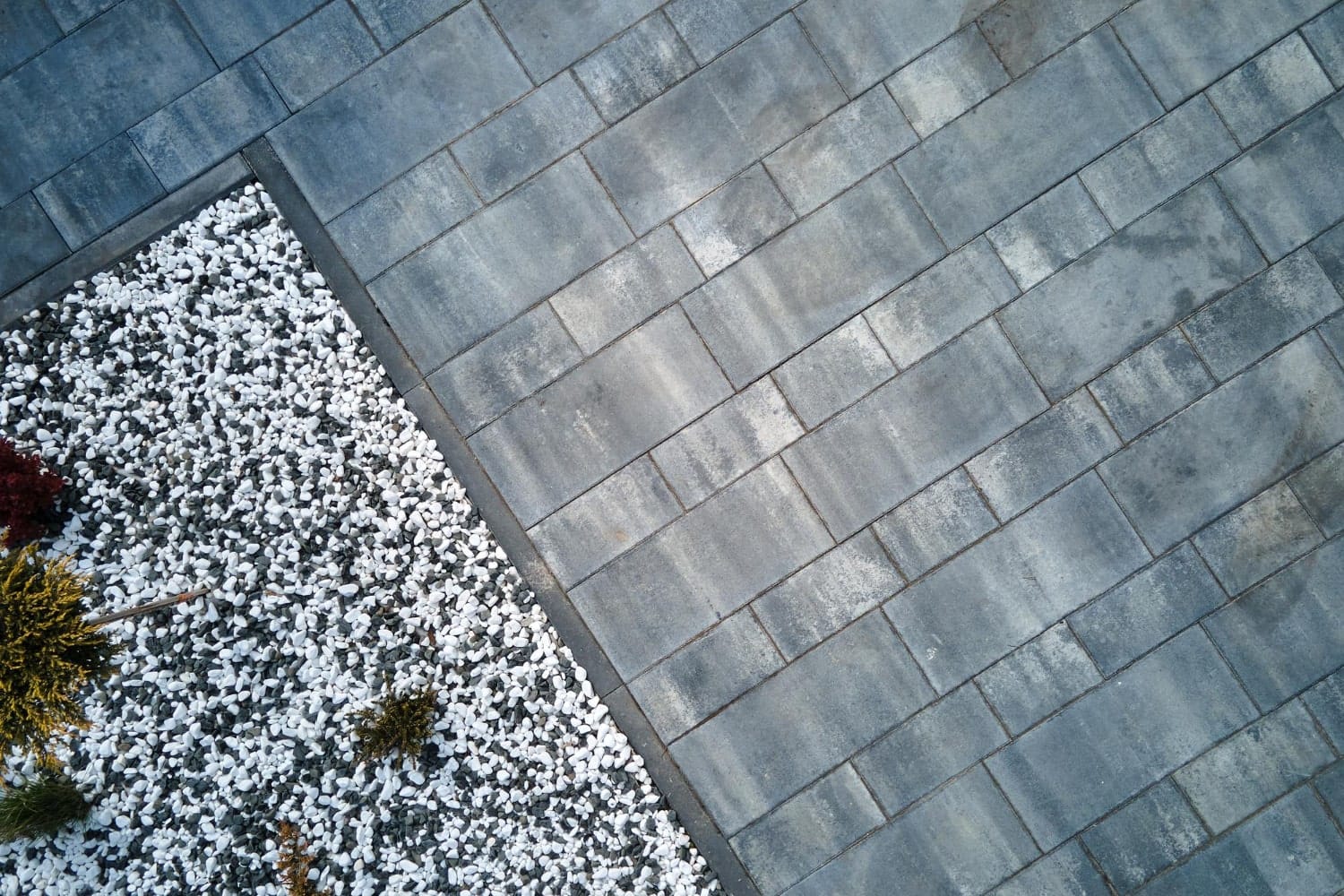 25127-min Aerial view of a gray stone paver patio beside a garden bed with white gravel and small plants.