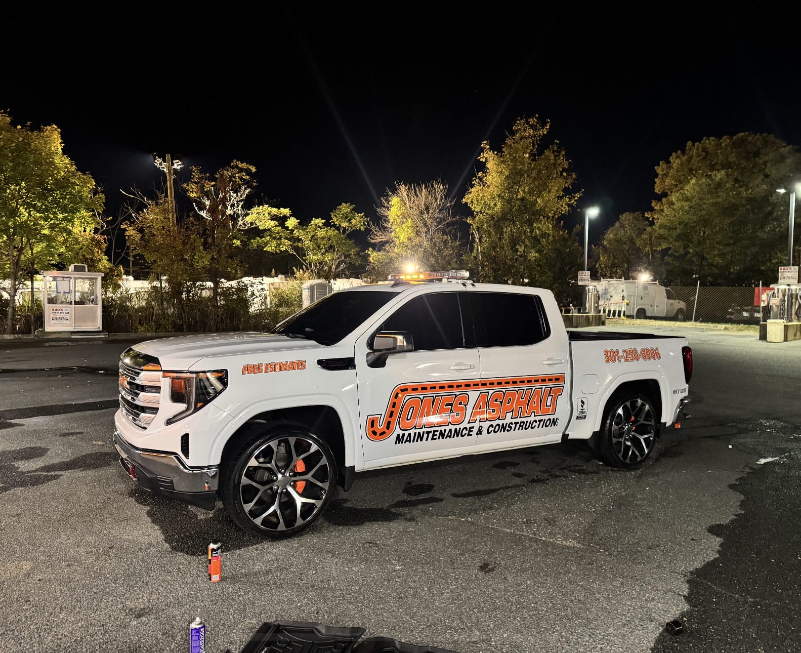 White pickup truck with "Jones Asphalt Maintenance & Construction" logo parked at night in a lot.